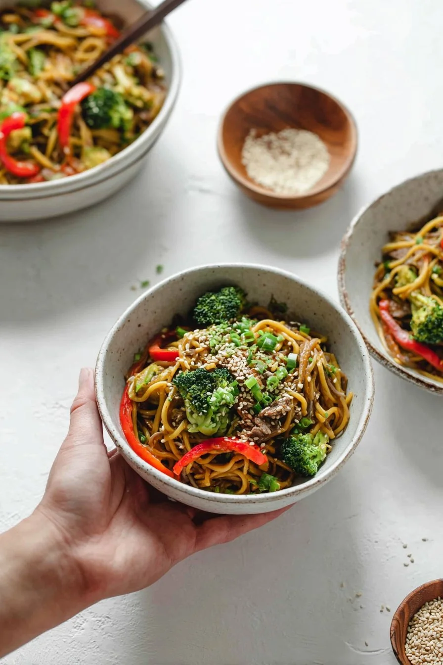Bowl of Sesame Ginger Beef Udon with beef, vegetables, and sesame seeds.